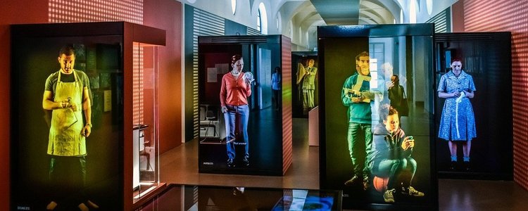 Ausstellung mit lebensgroßen Bildschirmen mit Menschen